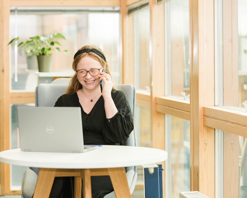 Woman laughing on the phone looking at her laptop