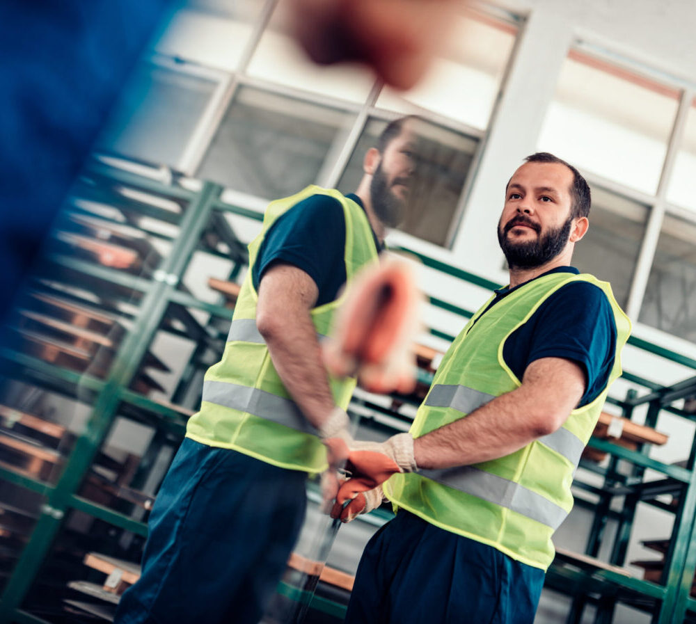 Warehouse workers carrying stainless steel inox sheet metal in factory