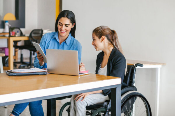 Hispanic woman in wheelchair with her colleagues at workplace